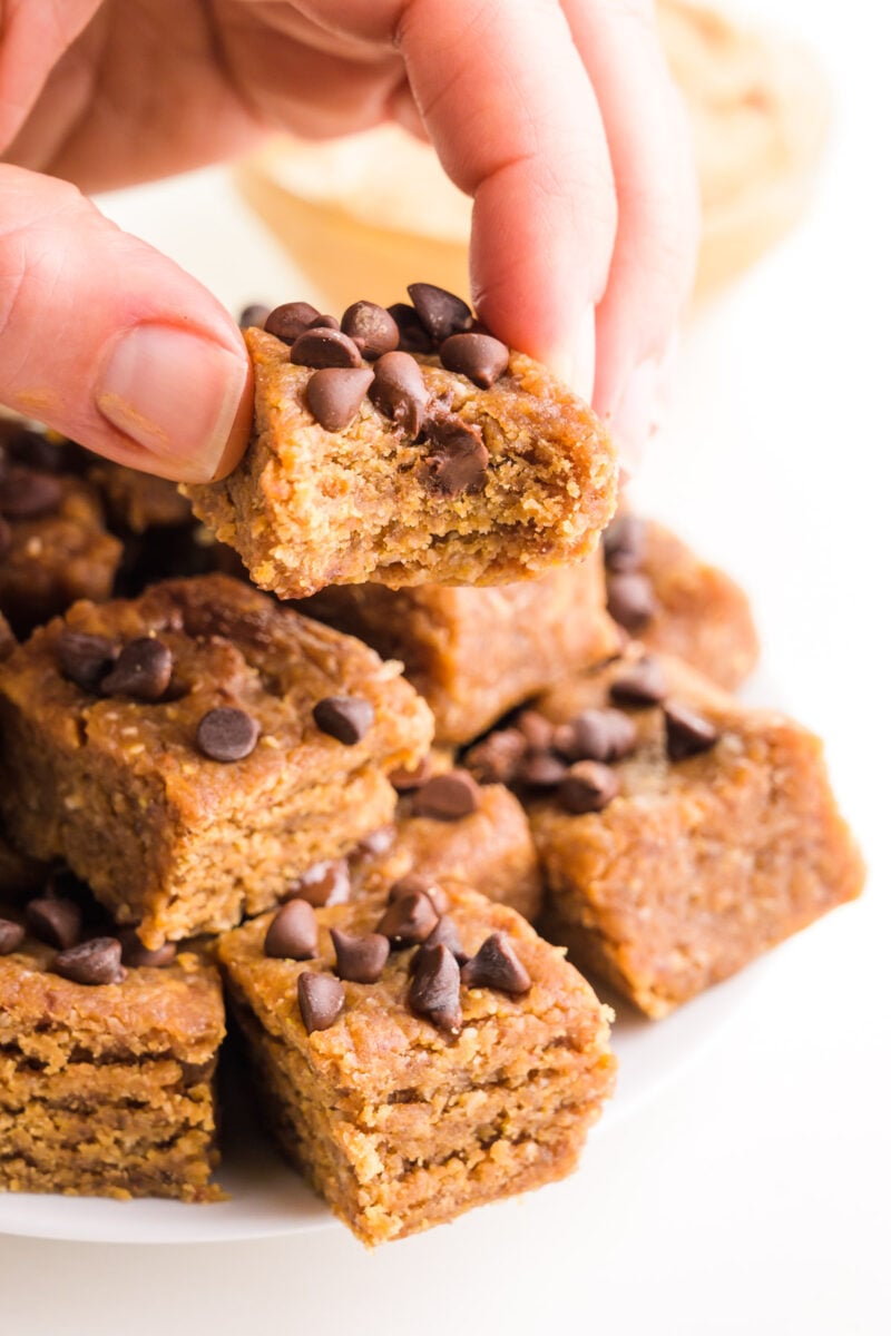 A hand holds a piece of fudge with a bite taken out. 