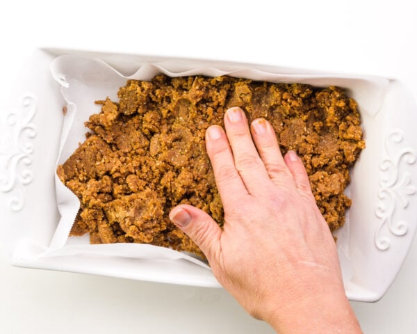 A hand presses down on a fudge mixture in a pan.