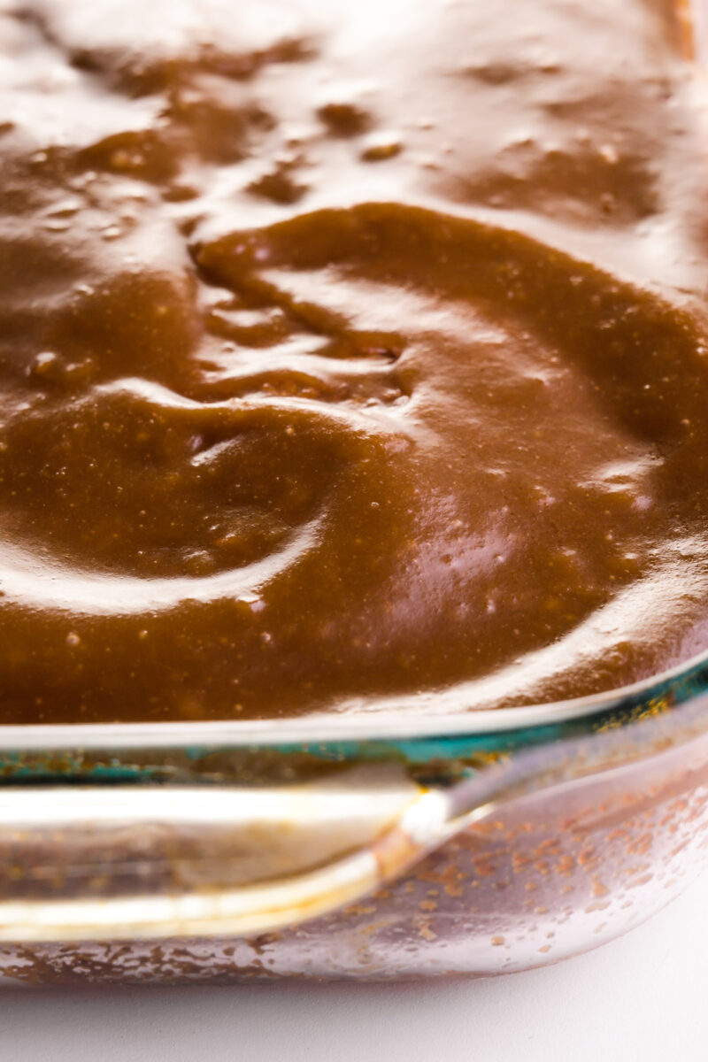 Looking down on a cake in a baking pan. The cake is covered with caramel frosting.