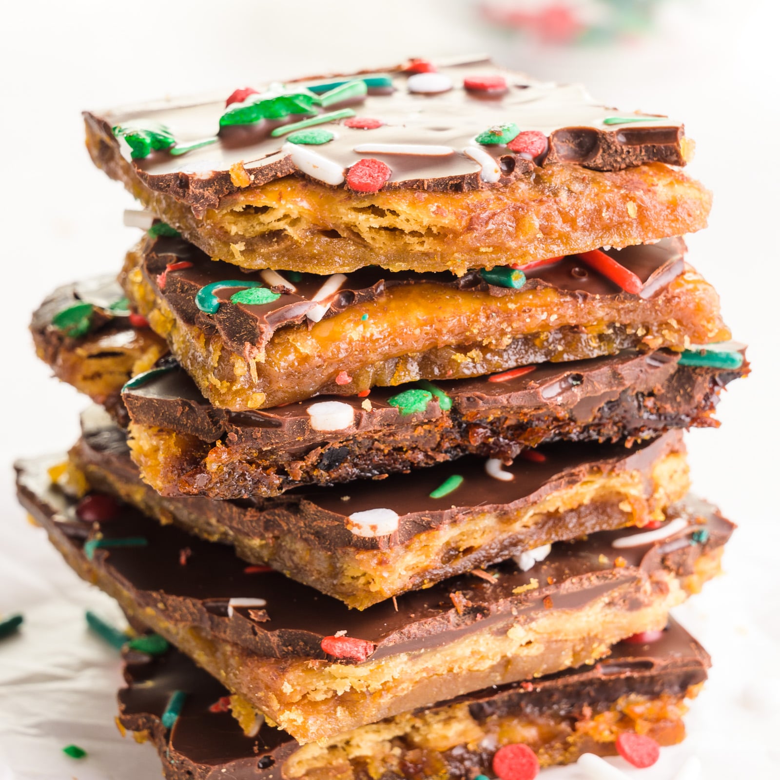 Vegan Christmas crack pieces are stacked on a white counter.