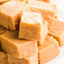 Pieces of vegan peanut butter fudge are stacked on a plate.