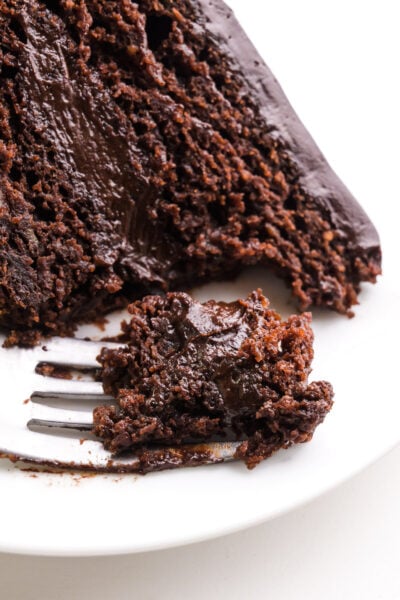 Looking down on a slice of cake on a plate. A bite has been taken and it sits on a fork.