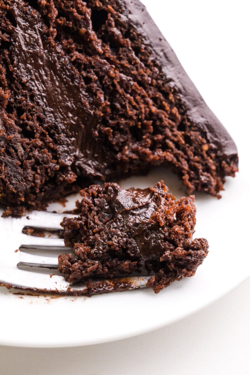 Looking down on a slice of cake on a plate. A bite has been taken and it sits on a fork.