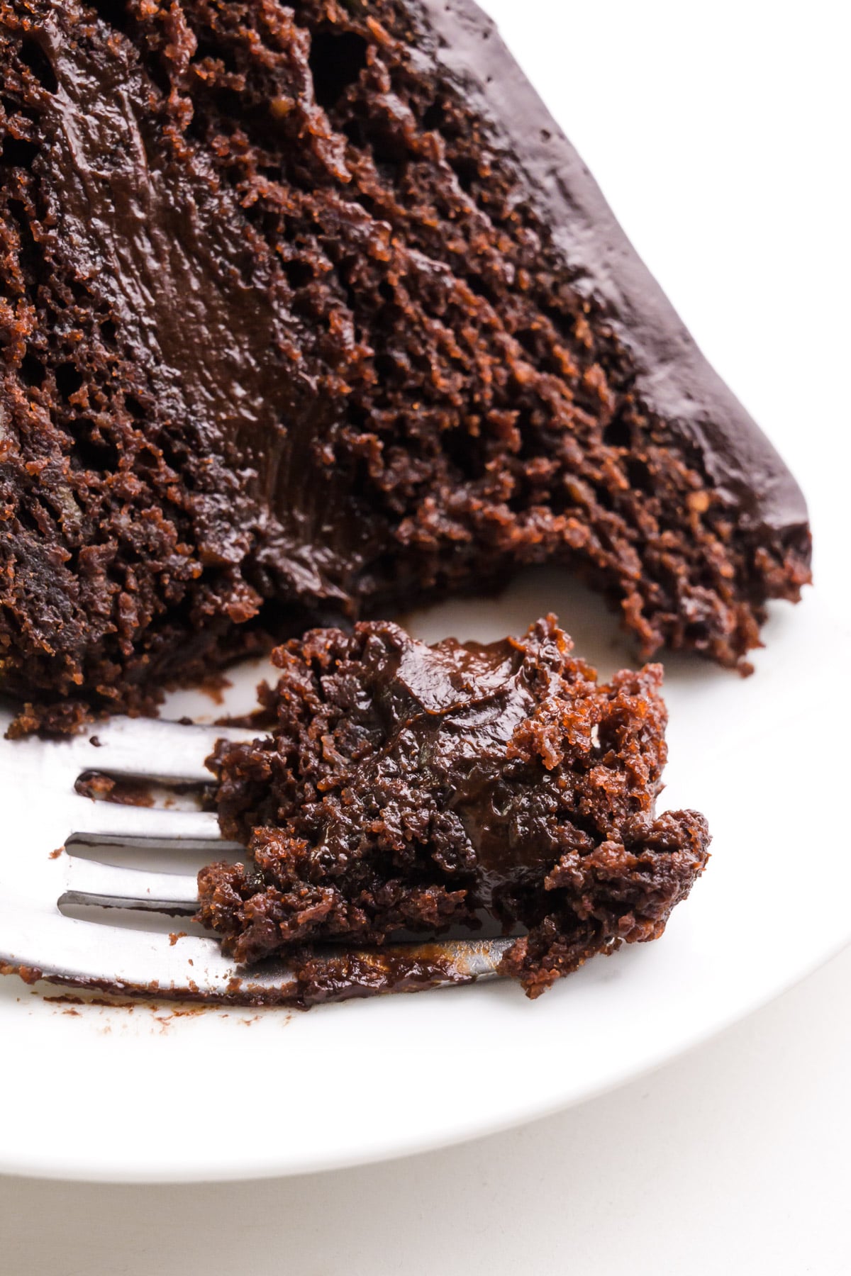 Looking down on a slice of cake on a plate. A bite has been taken and it sits on a fork.