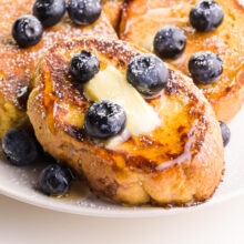 A closeup of a slice of Just Egg French Toast with blueberries, melted vegan butter, and maple syrup.