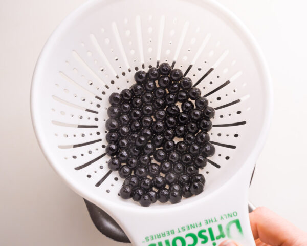 Freshly cooked boba pearls are in a strainer.
