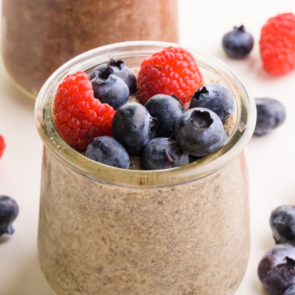 A closeup of chia pudding in a jar with fresh fruit on top.