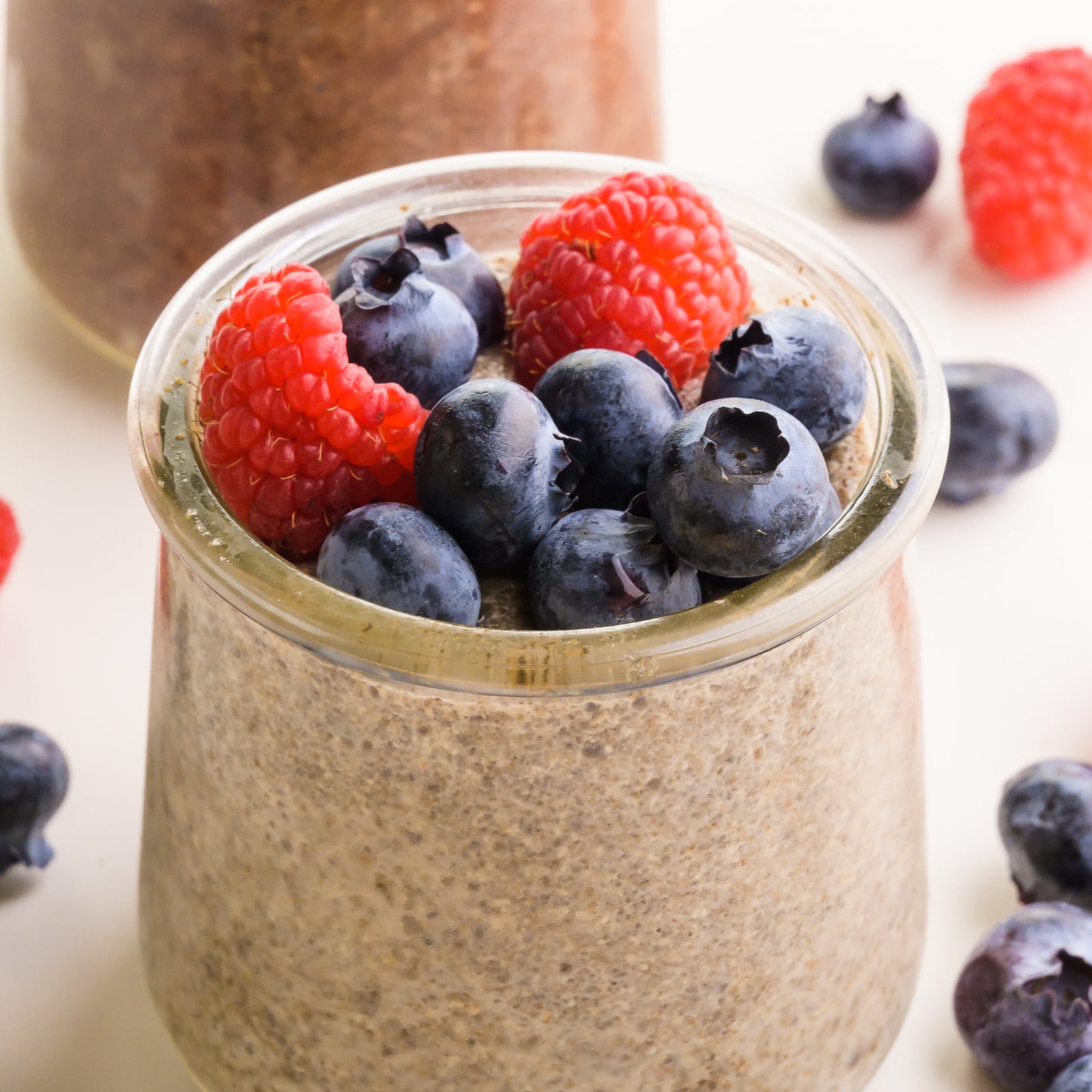 A closeup of chia pudding in a jar with fresh fruit on top.