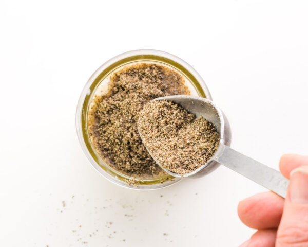 A hand pours chia seeds into a bowl.