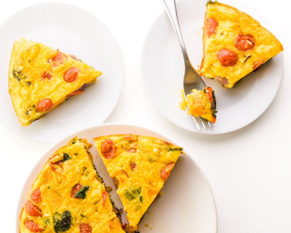 Looking down on slices of vegan frittata on plates. One has a fork next to it with a bite taken out.