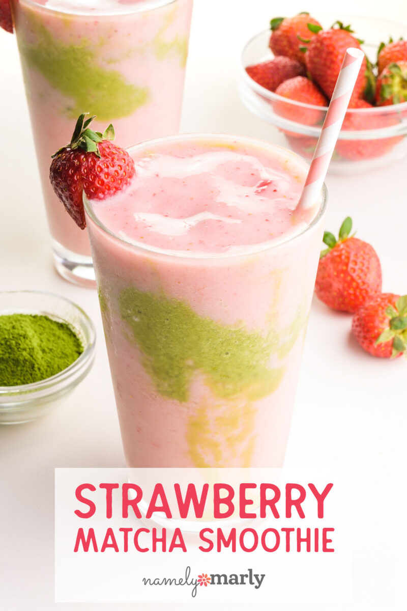 Strawberry matcha smoothie in a glass with a pink straw; strawberries and matcha powder are nearby.