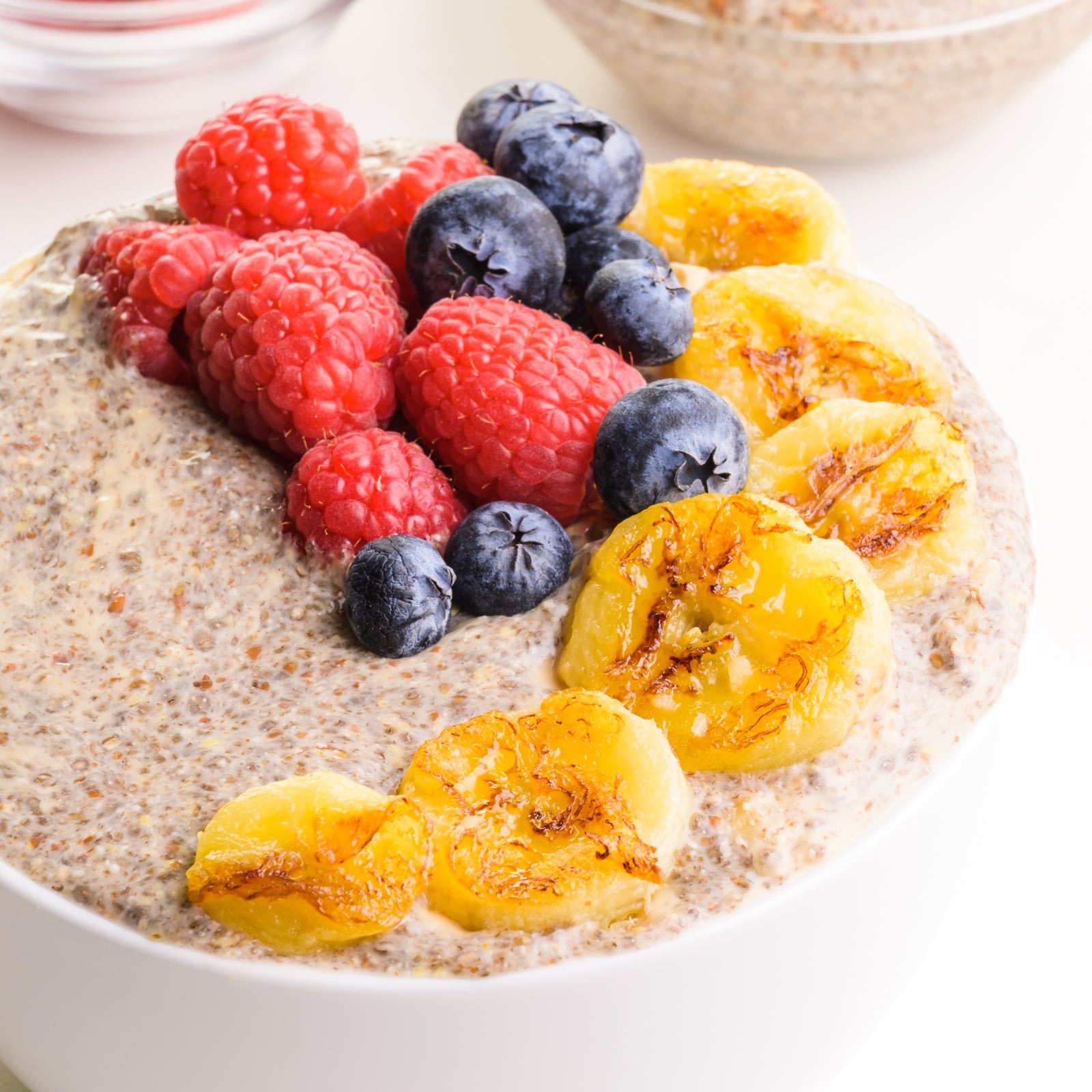A closeup of hot chia pudding with seared bananas and fresh berries on top.