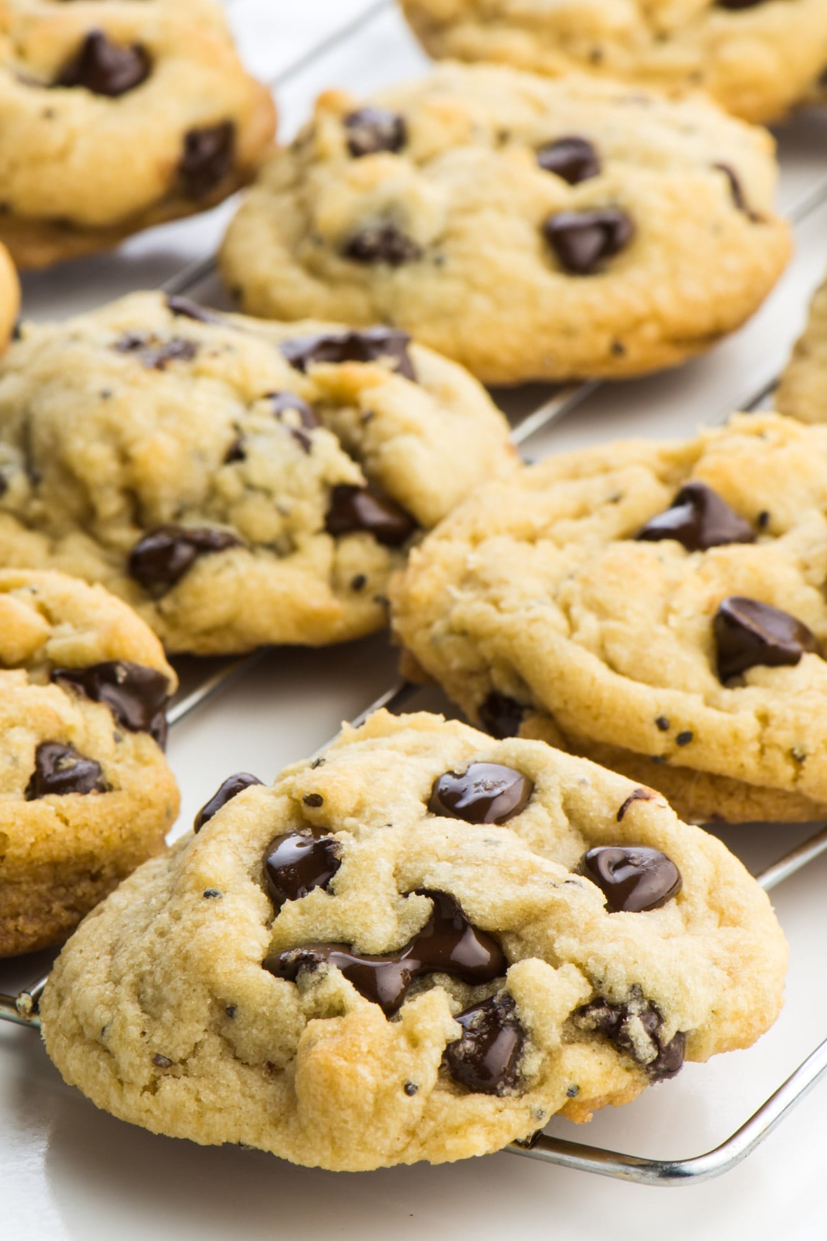 Vegan chocolate chip cookies sit on a wire rack, after having just been removed from the oven.