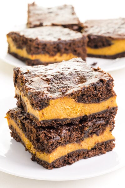 A stack of vegan pumpkin brownies sit in front of more brownies in the background.