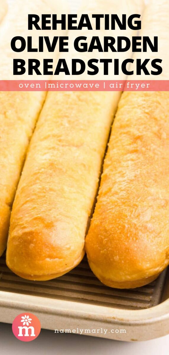 Three freshly baked breadsticks on a baking tray with text about reheating methods.