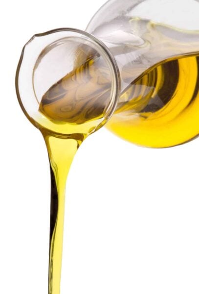 Olive oil is being poured from a glass pitcher.