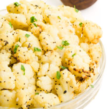 A bowl of air fried frozen cauliflower has fresh herbs on top.