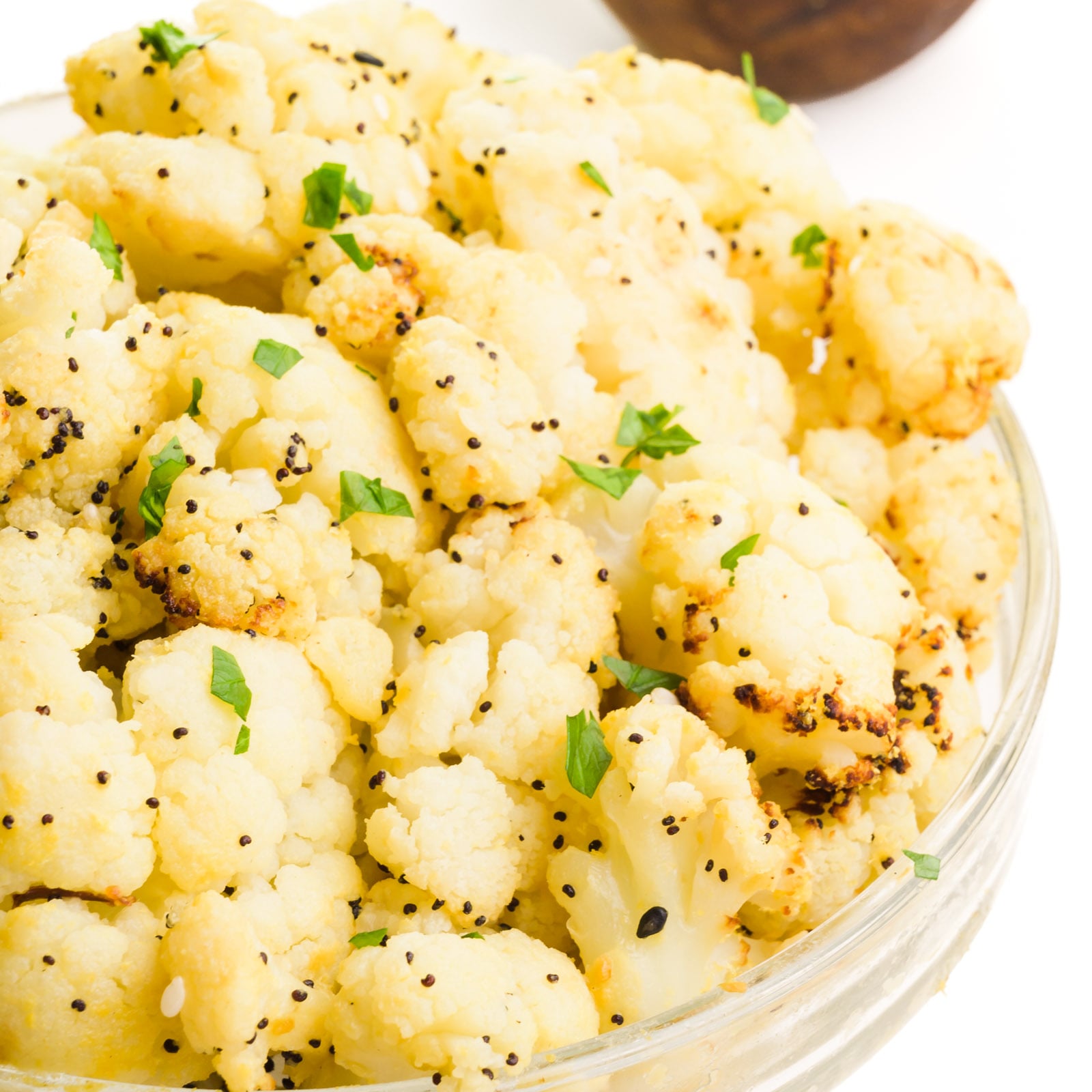 A bowl of air fried frozen cauliflower has fresh herbs on top.