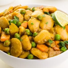 A closeup of butter bean curry in a bowl with a slice of lime on top.