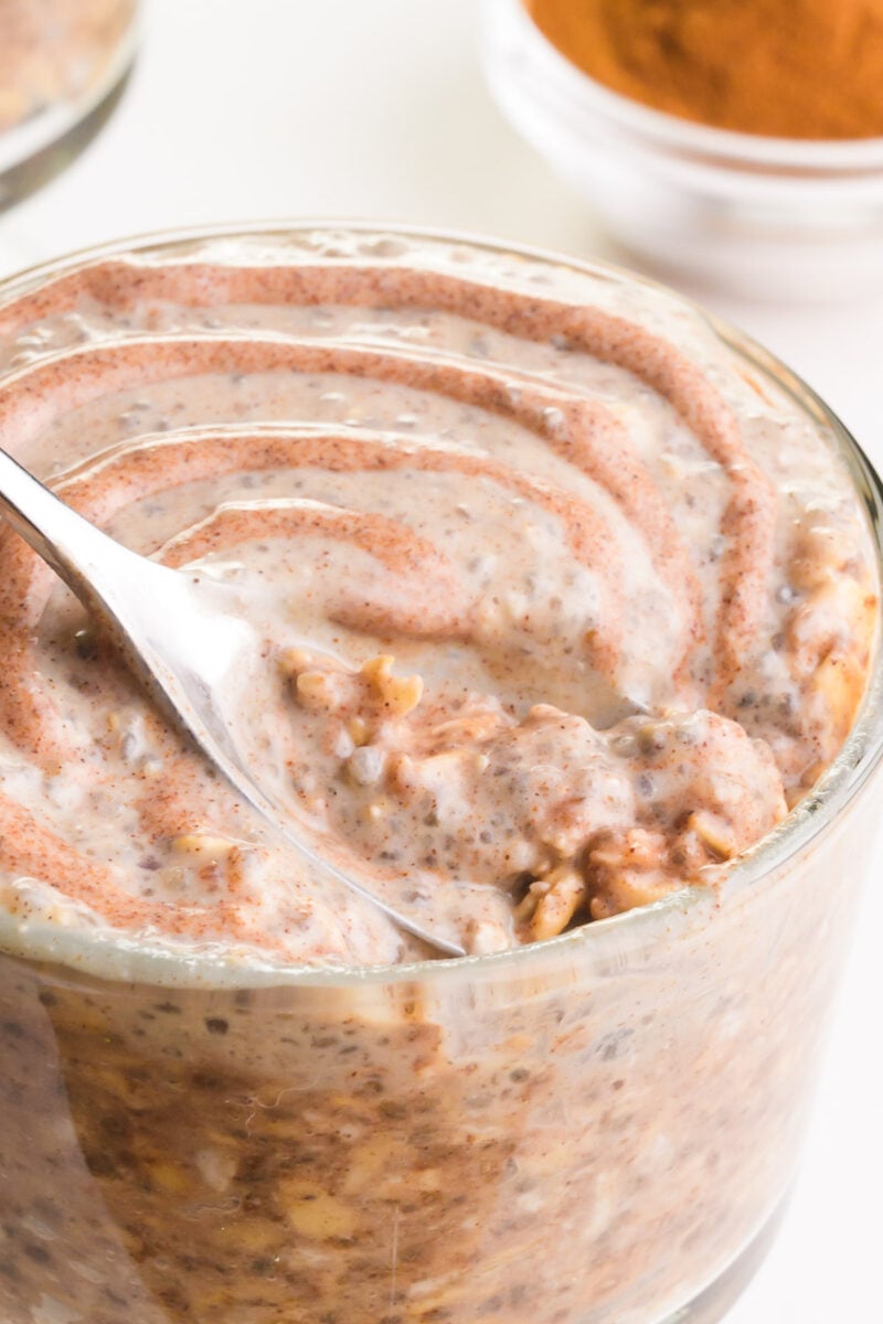 Looking down into a bowl of cinnamon overnight oats with a spoon in it.