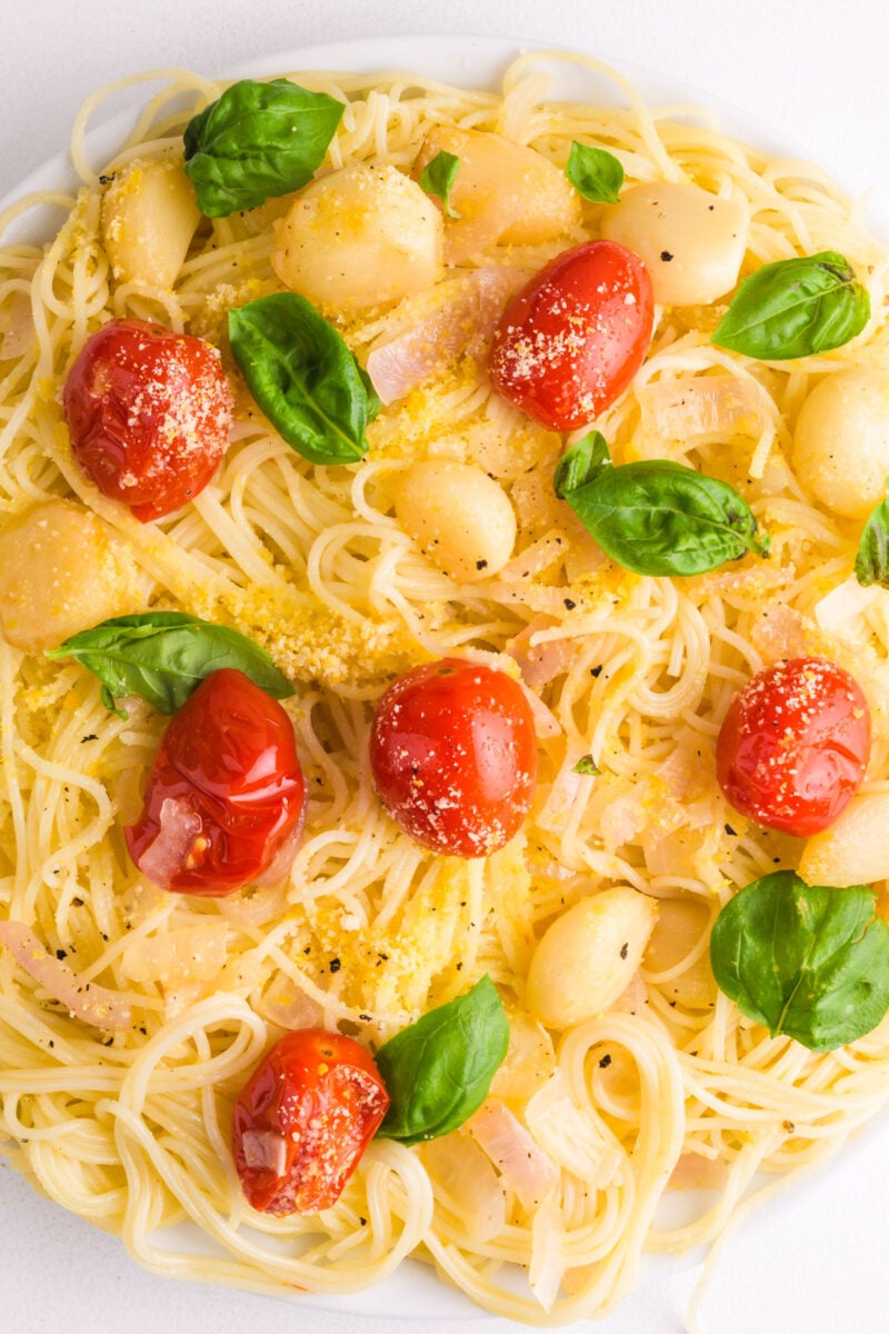 Looking down on a plate of pasta with tomatoes, garlic, and fresh basil.