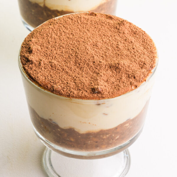 A bowl of vegan tiramisu overnight oats sits on a white table.