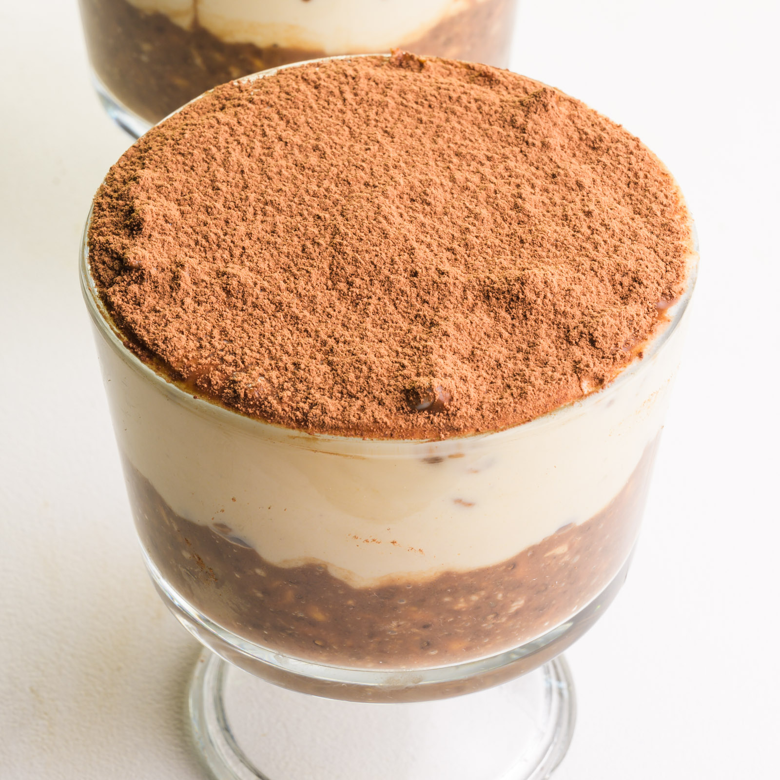 A bowl of vegan tiramisu overnight oats sits on a white table.