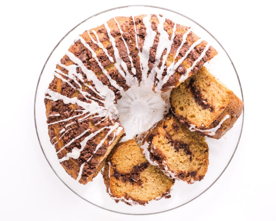 Looking down on a coffee cake on a dish, with a few slices sitting beside it.