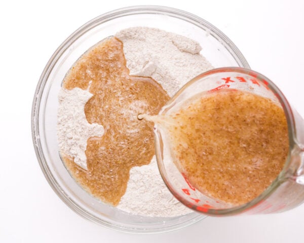 Wet ingredients are being poured into a bowl with flour ingredients.