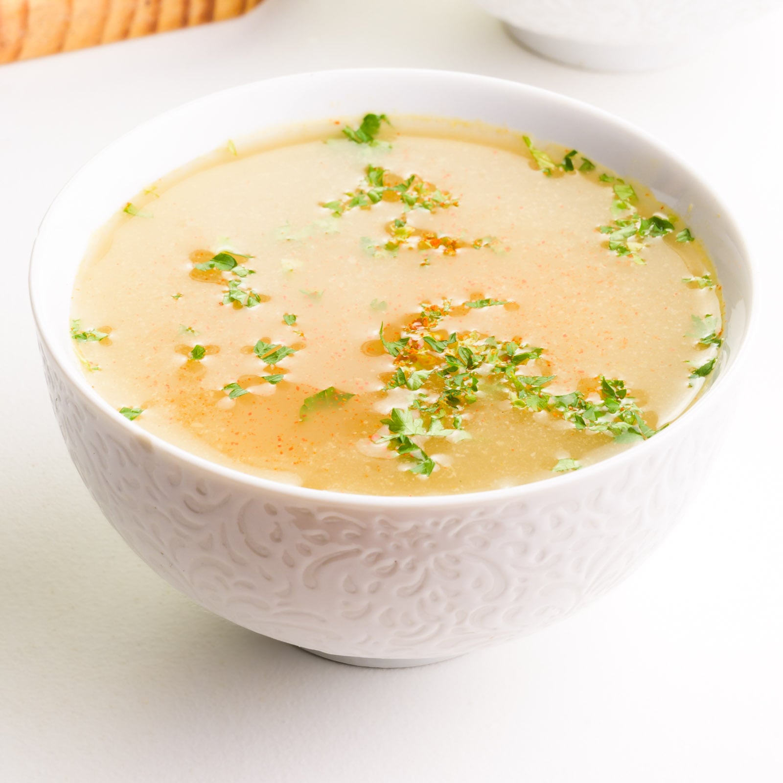 A bowl of biome broth has fresh herbs and a sprinkle of paprika on top.