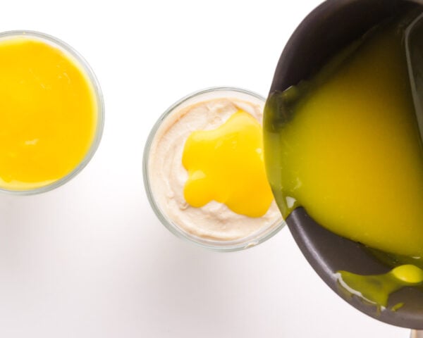 Lemon curd is being poured into a creamy dessert dish.
