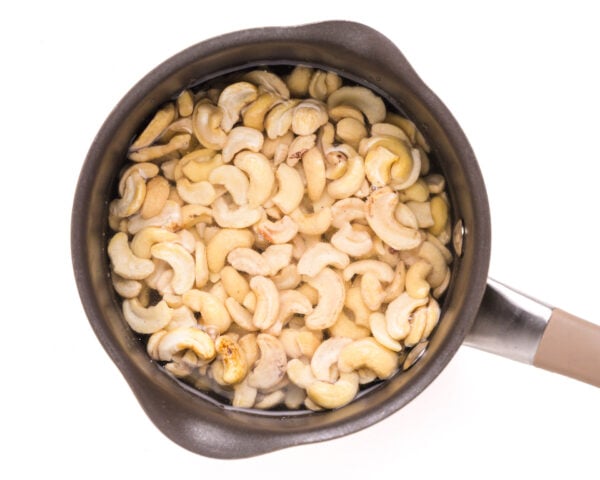 Looking down on a saucepan with cashews soaking in water.