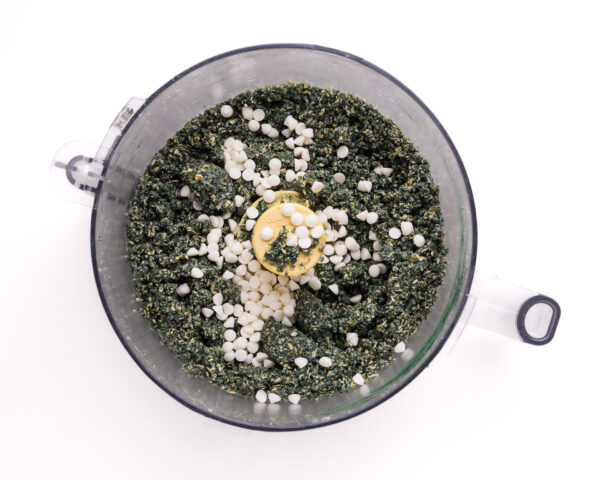 Looking down on ingredients in a food processor bowl, including white chocolate chips.