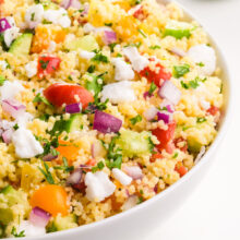 Looking into a bowl of vegan couscous salad with lots of veggies on top.