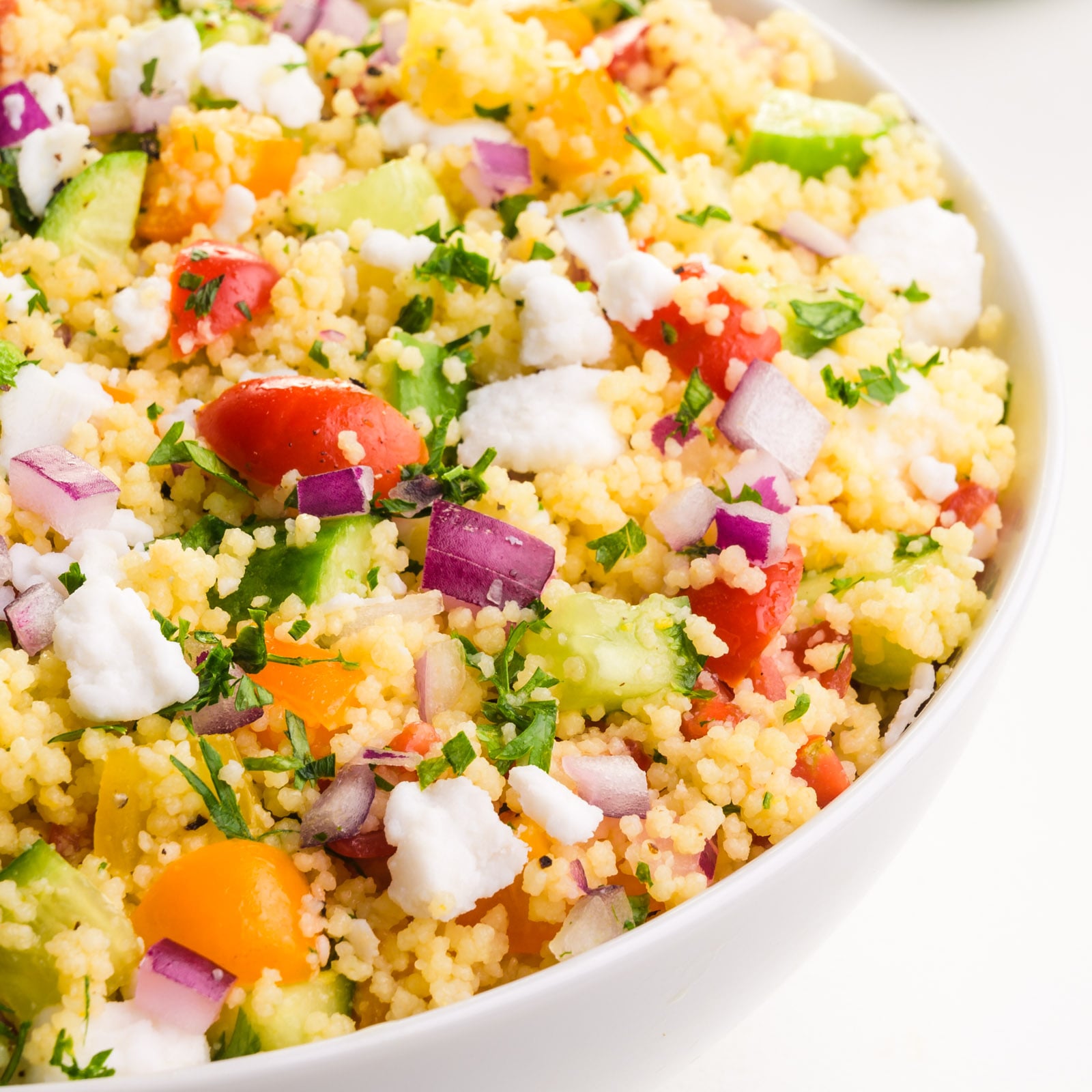 Looking into a bowl of vegan couscous salad with lots of veggies on top.