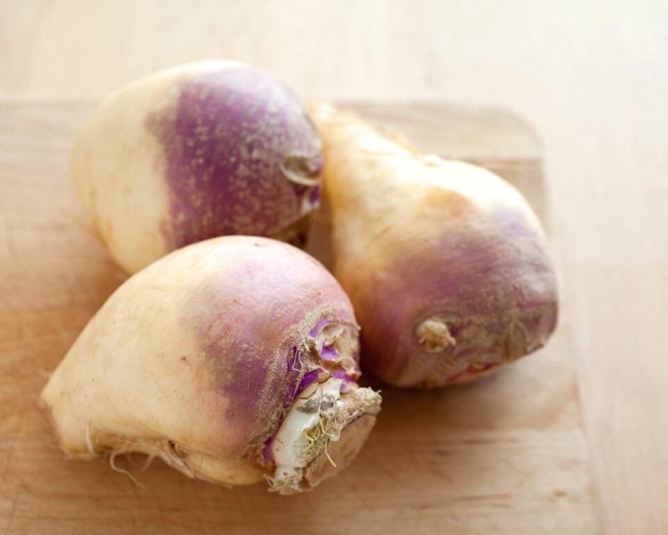 A picture of rutabagas sitting on a wooden cutting board.
