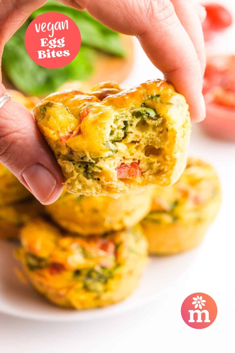 A hand holds an egg bite with a bite taken out. The text reads, Vegan Egg Bites.