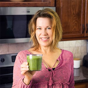 Marly holding a small glass of green smoothie