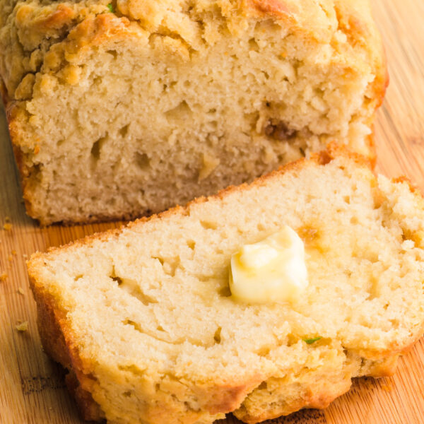 A slice of plant-based beer bread sits in front of the rest of the loaf.