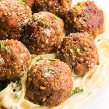 A plate of pasta with cream sauce is topped with several Impossible Meatballs.