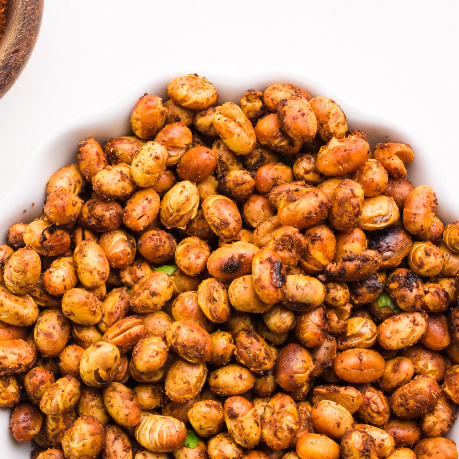 Looking down on a bowl of roasted soybeans sitting next to a bowl of spices.