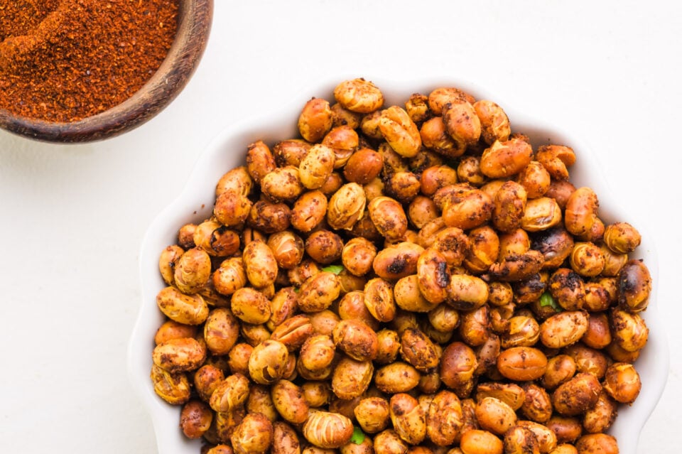 Looking down on a bowl of roasted soybeans sitting next to a bowl of spices.