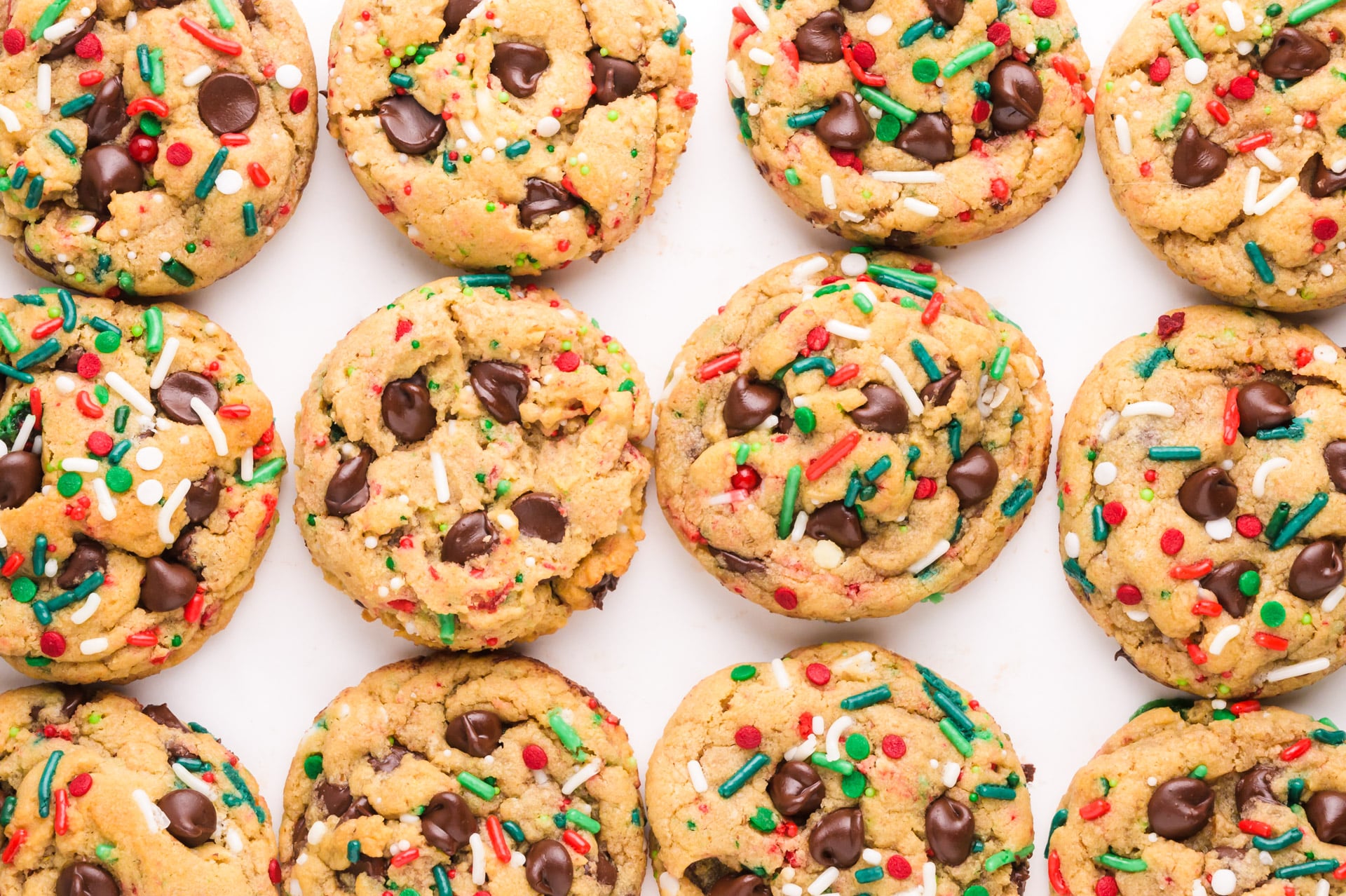 Looking down on chocolate chip christmas cookies side by side on a white counter.