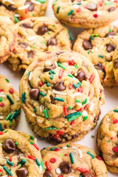 Looking down on a batch of Christmas chocolate chip cookies, a few of which are stacked on top of each other.