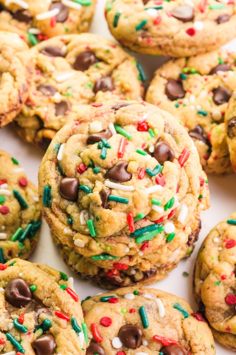 Looking down on a batch of Christmas chocolate chip cookies, a few of which are stacked on top of each other.