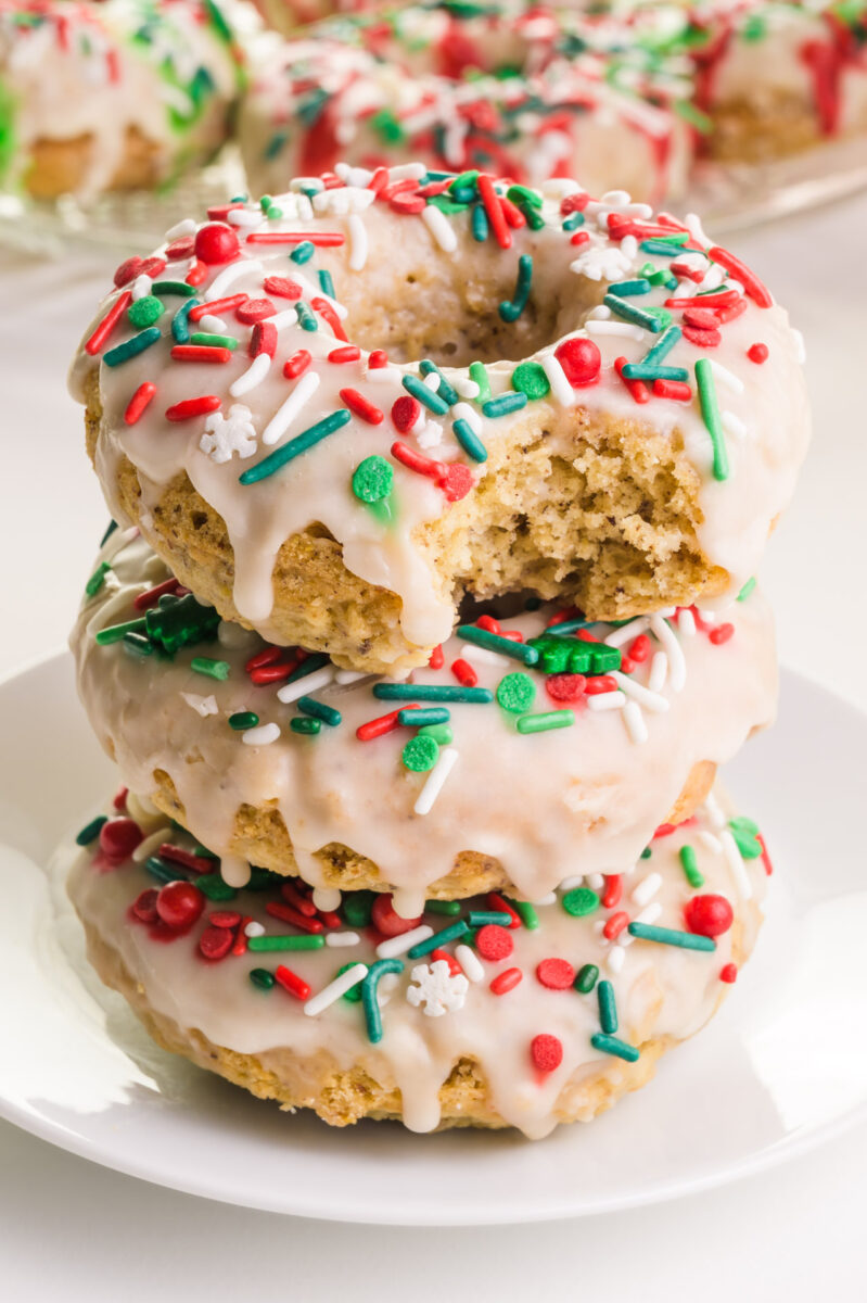 A stack of vegan Christmas donuts shows the top one with a bite taken out.