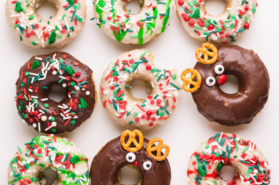 Looking down on Christmas donuts lined up on a white counter.