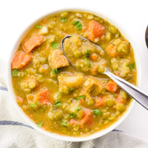 Looking down on a bowl of vegetarian split pea soup with a spoon in it.