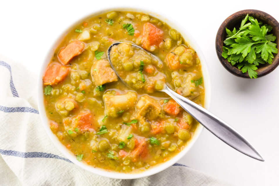 Looking down on a bowl of vegetarian split pea soup with a spoon in it.