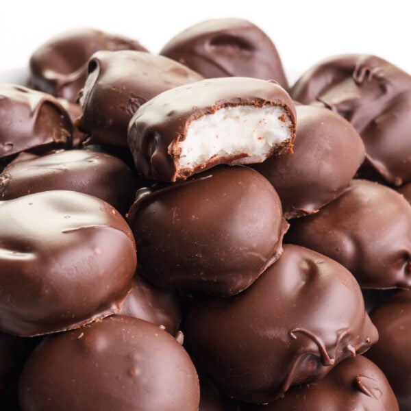 A vegan junior mint with a bite taken out sits on top several of the candies.